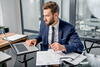 a man in a suit is working on reports in his office